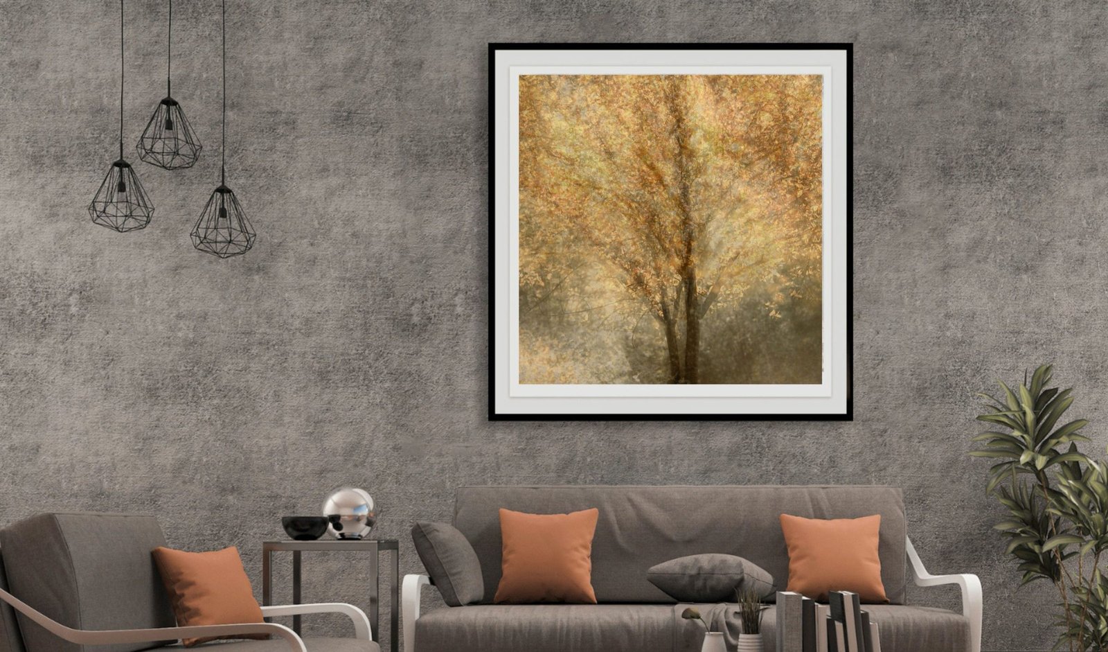 A golden tree artwork in a thin black frame on a concrete wall above a sofa