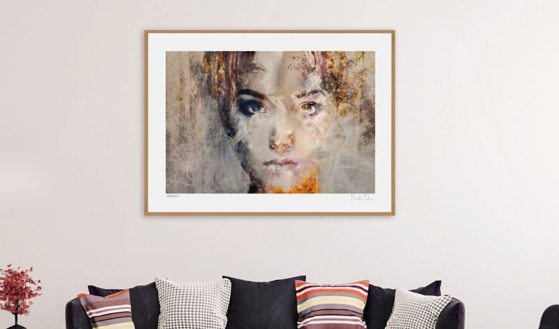 Portrait artwork in a light wood frame above a sofa