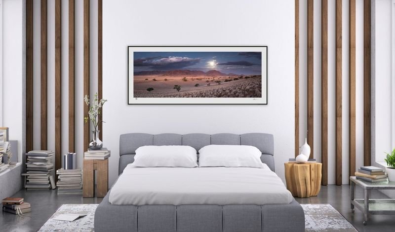 Moonlit panorama in a dark frame above a bed