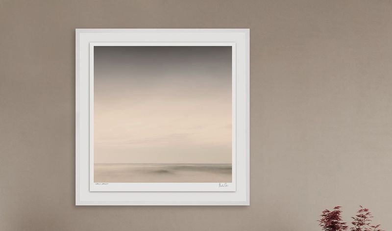 Soft seascape in a white box frame on a warm wall