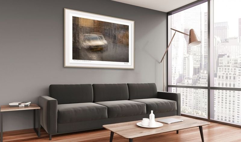 Classic car photograph in a white frame above a sofa