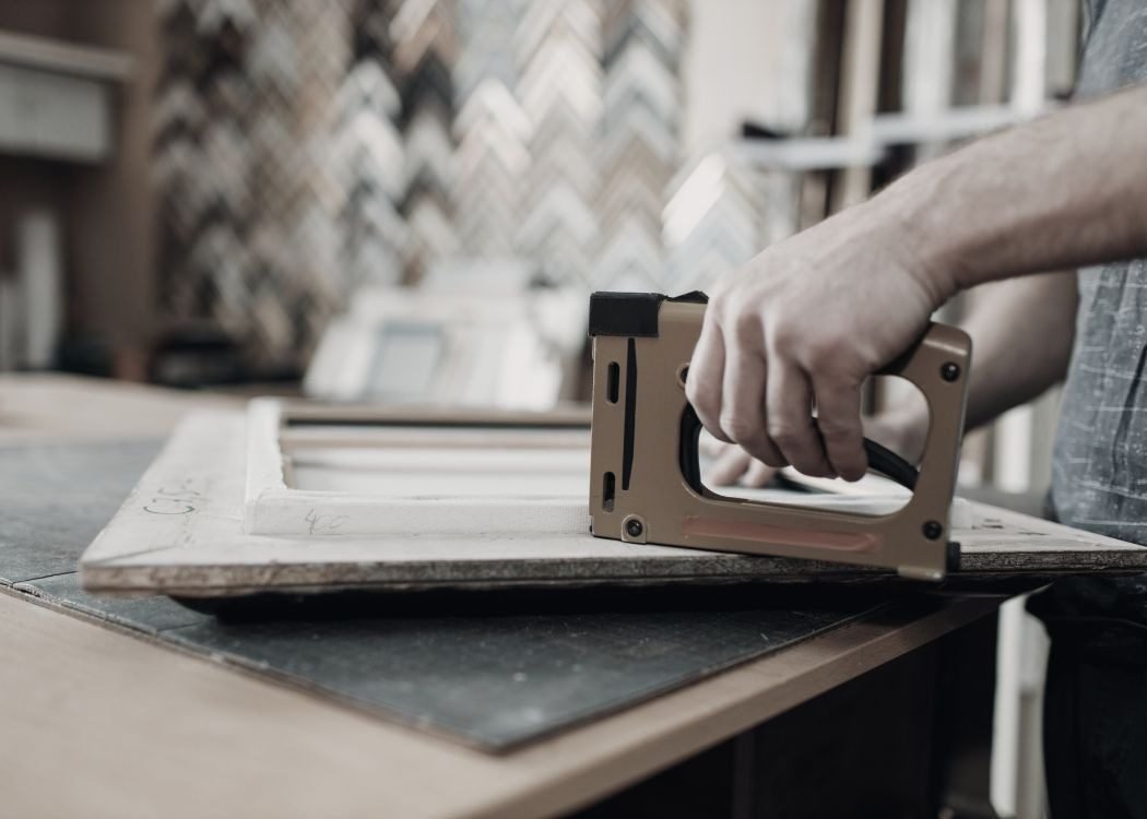 Stapling the back of a wooden frame at the workbench in the framing workshop
